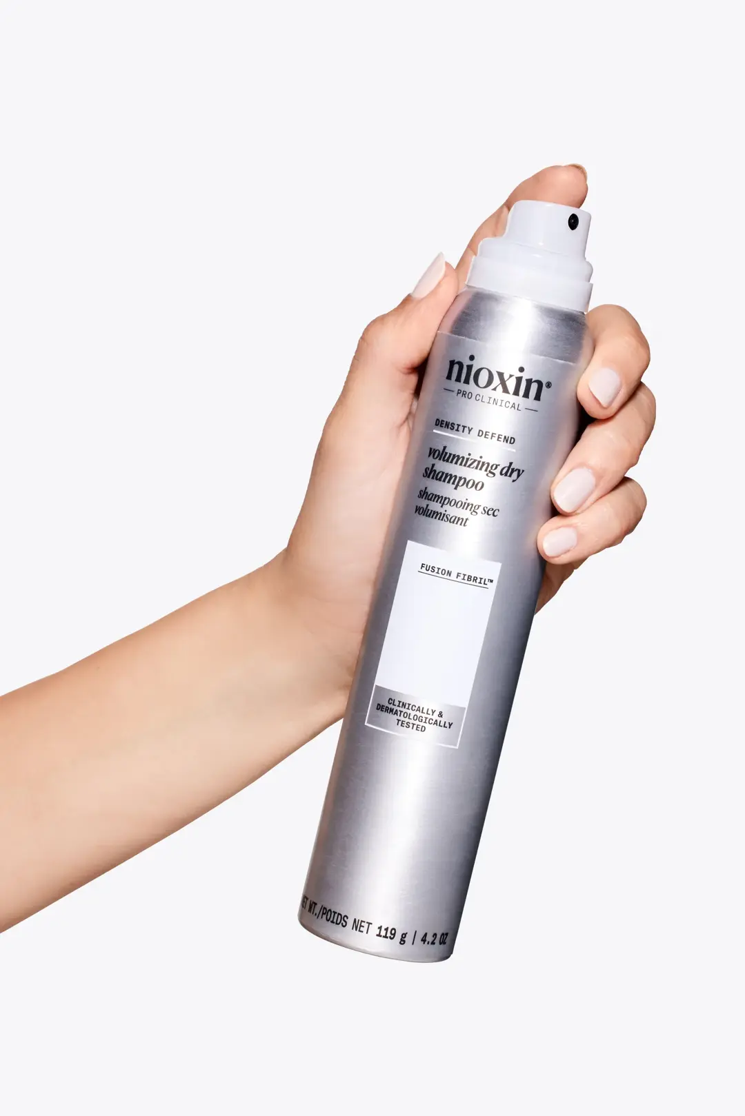 Volumising Dry Shampoo de Nioxin en una mano sobre un fondo blanco
